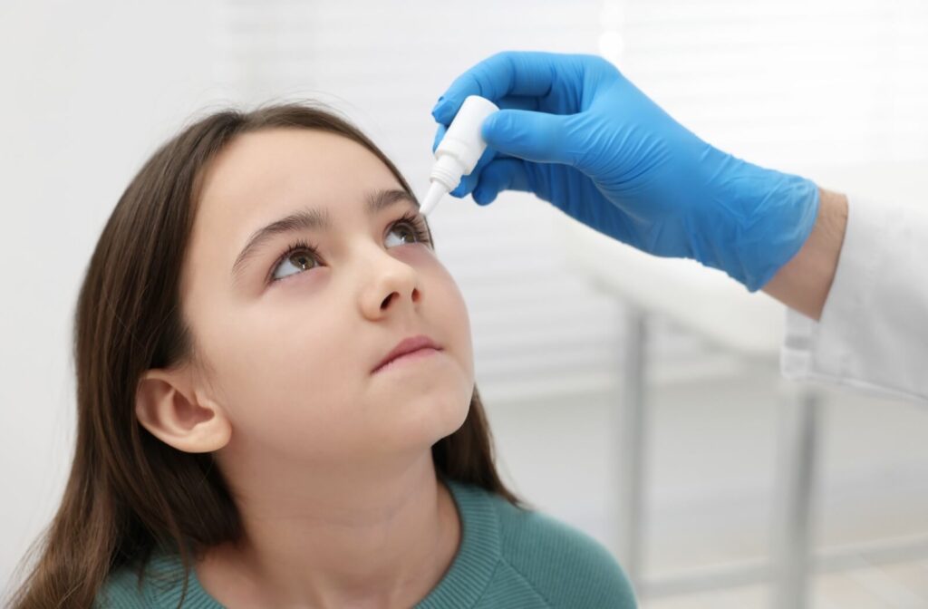 An optometrist putting atropine eye drops in a child's eyes to help with myopia