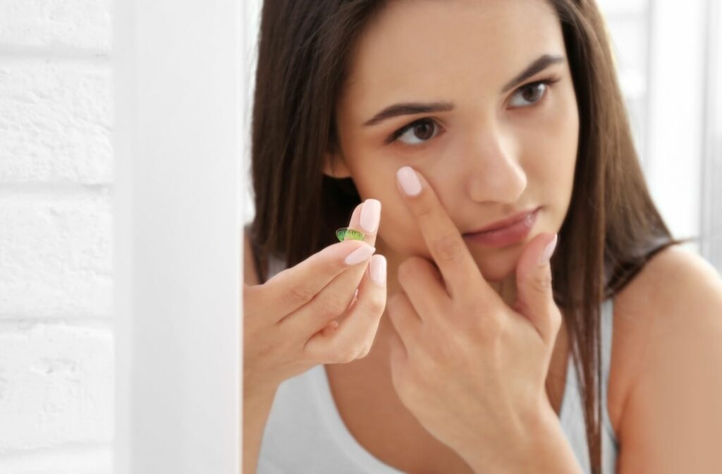A young person inserting a contact lens into their eye.