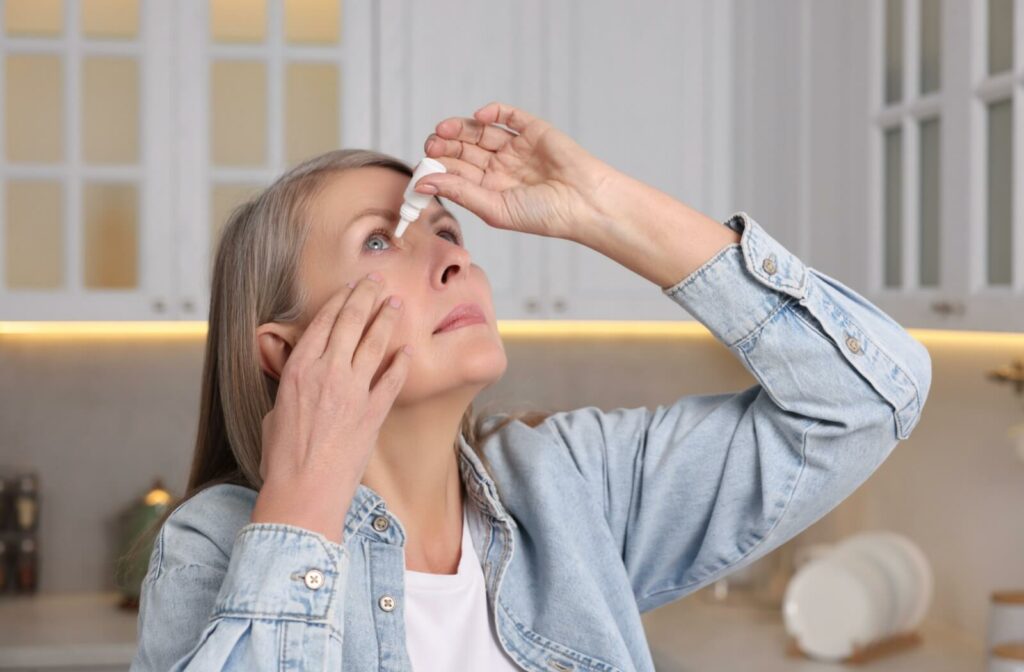 An adult putting eye drops in their eyes.